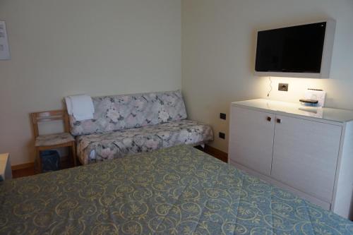 a bedroom with a bed and a couch and a flat screen tv at Hotel Columbus in Lignano Sabbiadoro