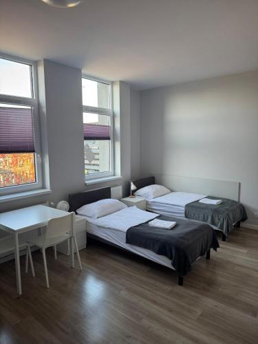 a room with two beds and a table and two windows at Hostelik Przy Przystanku in Gryfino
