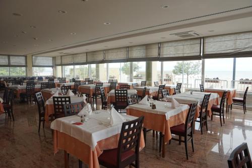 a dining room with tables and chairs and windows at Hotel Columbus in Lignano Sabbiadoro