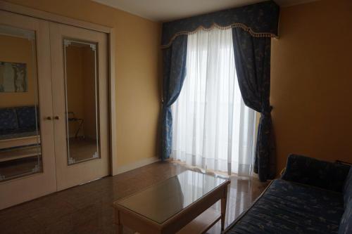 a living room with a table and a window at Hotel Columbus in Lignano Sabbiadoro