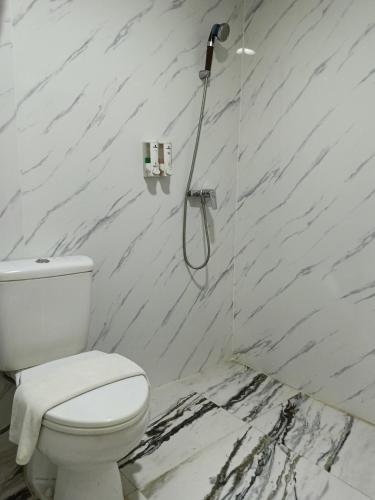 a bathroom with a toilet and a shower at Lux Tychi Hotel in Malang