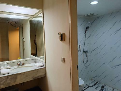 a bathroom with a sink and a shower with a mirror at Lux Tychi Hotel in Malang