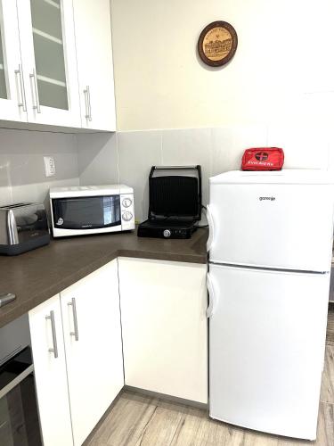 a kitchen with white cabinets and a microwave and a refrigerator at ALOM in Osijek