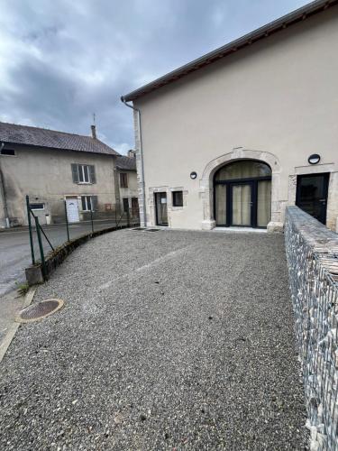 a white building with a fence next to a street at Appartement proche du lac de Vouglans in Charchilla