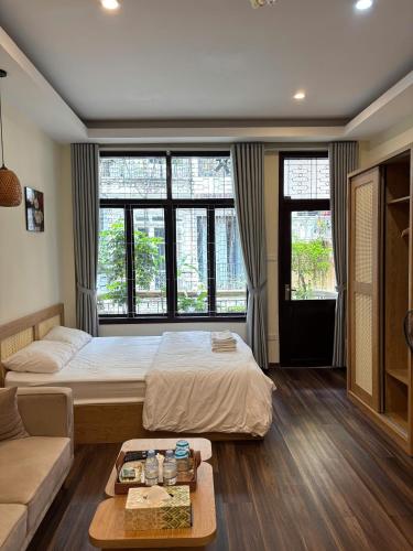 a bedroom with a bed and a couch and windows at An Thuong House - Hoan Kiem, Hanoi Center in Hanoi