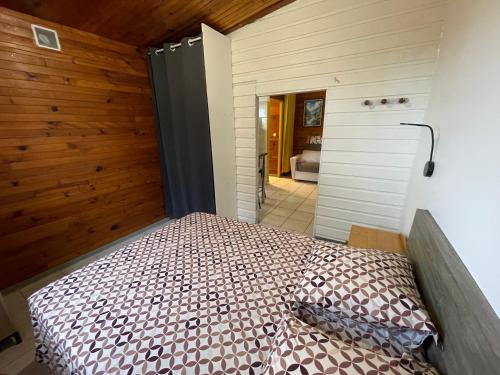 a bedroom with a bed in a room with wooden walls at GITE-Hotel LA CAZ DES ORANGERS in Le Bois de Nèfles