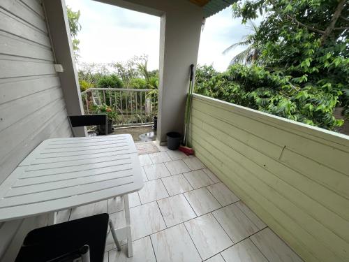 a porch with a white bench on the side of a house at GITE-Hotel LA CAZ DES ORANGERS in Le Bois de Nèfles