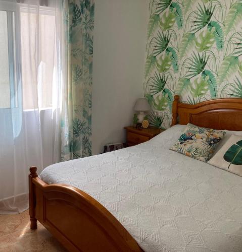 a bedroom with a bed with a tropical wallpaper at Charming duplex with pool in Torrevieja