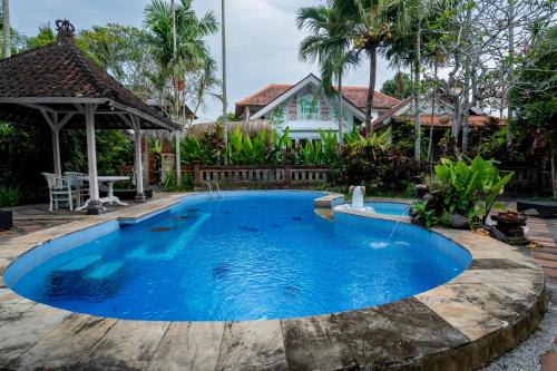 a pool in a backyard with a house in the background at Eiwa House in Ubud