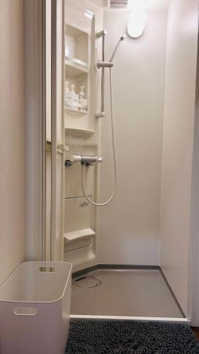 a bathroom with a shower and a toilet in it at 古民家ゲストハウス ナマケモノ in Ōno