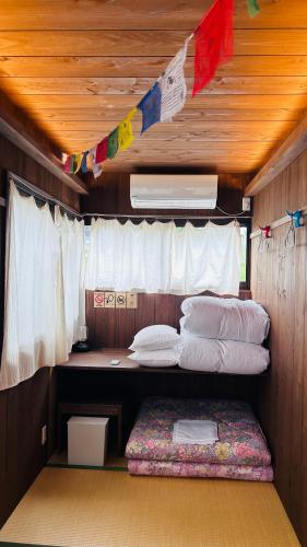 a room with two beds and a window with flags at 古民家ゲストハウス ナマケモノ in Ōno