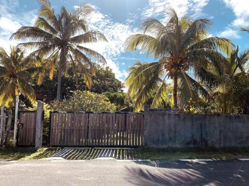 a wooden fence with palm trees in the background at Cottage 50 m from the beach in Mauritius