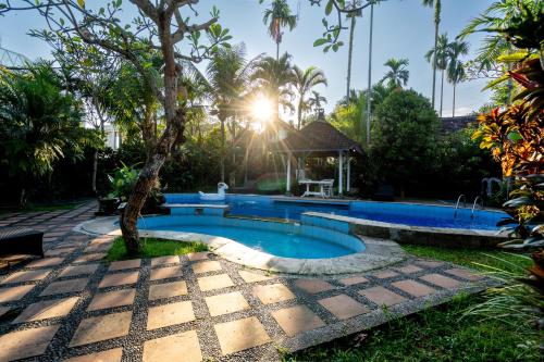 a swimming pool in a garden with a palm tree at Eiwa House in Ubud