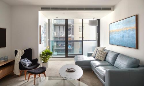 a living room with a couch and a table at City Escape - 8 mins From Flinders St - Pool & Gym in Melbourne