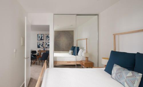 a bedroom with a white bed and a mirror at City Escape - 8 mins From Flinders St - Pool & Gym in Melbourne