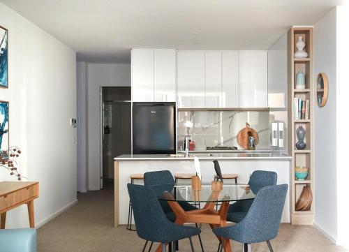 a kitchen with a glass table and blue chairs at City Escape - 8 mins From Flinders St - Pool & Gym in Melbourne