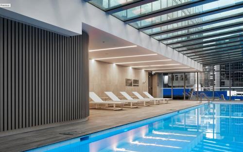 a swimming pool with lounge chairs next to a building at City Escape - 8 mins From Flinders St - Pool & Gym in Melbourne