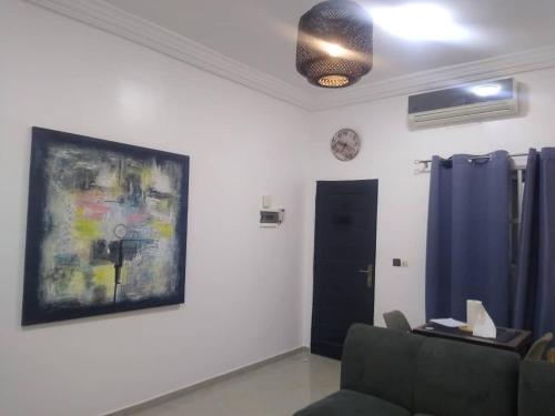 a living room with a couch and a painting on the wall at Résidence ILEWA proche mer avec Terrasse Fidjrosse Cotonou in Cotonou