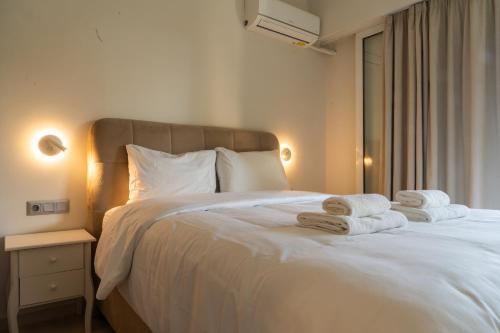 Palm & Pearl Apartment في أثينا: غرفة نوم بسرير ابيض عليها مناشف