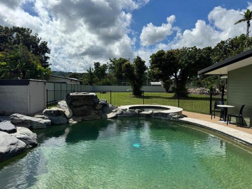 a swimming pool with rocks in a yard at Jabiru Stay Daintree Village in Daintree