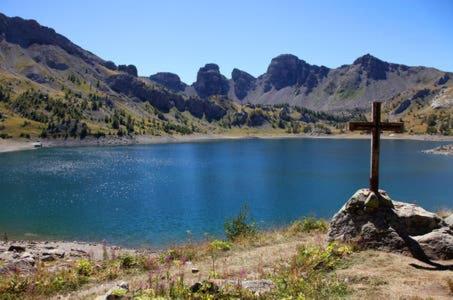 a cross on a rock in front of a lake at La Foux d'Allos Vacances nature Espace Lumière in La Foux