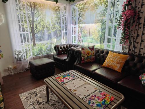 a living room with a leather couch and a large window at Relax & Recharge - a Unique Suite with a Touch of Luxury - Hot Tub and Sauna Inspired Decor #NOT A REAL SAUNA# Easy City Access - direct train 15 min to city in Helsinki