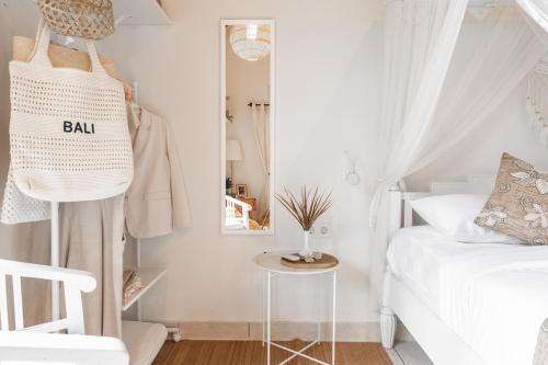 Moon & Honey villa في أوبود: غرفة نوم بيضاء مع سرير ومرآة