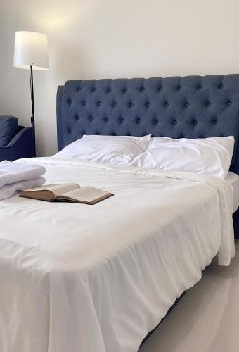 a white bed with a blue headboard and two books on it at Pollux Habibie Lvl 52 Sea View Studio with Gym,Pool & Netflix in Batam Center
