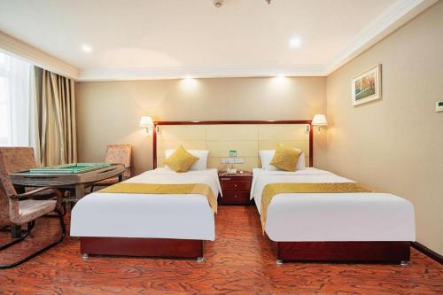 a hotel room with two beds and a desk at GreenTree Inn Taiyuan PinGYAng Road Business Hotel in Taiyuan