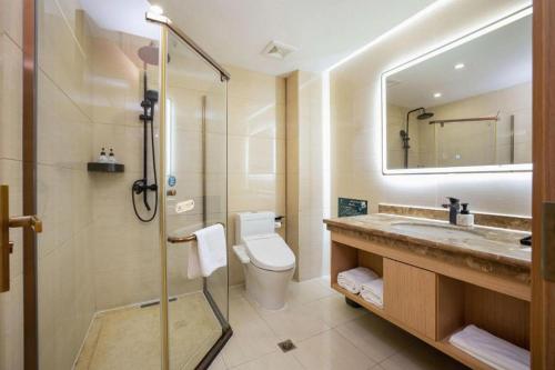 a bathroom with a toilet and a sink and a mirror at GreenTree Inn Taiyuan PinGYAng Road Business Hotel in Taiyuan