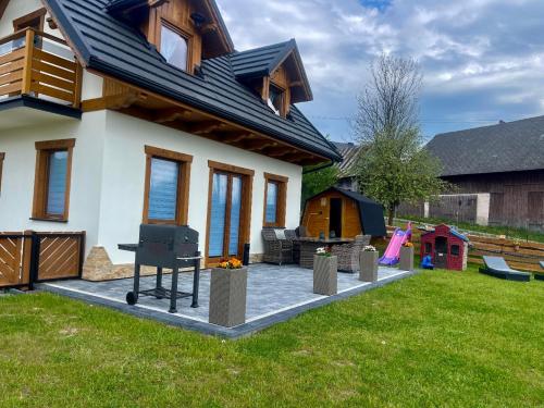 a house with a grill in the yard at Domki Odskocznia in Maniowy