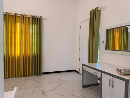 a living room with yellow curtains and a desk at VIVICA Airport Residence in Andimulla