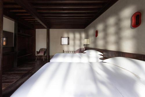 a bedroom with two white beds and a television at Lijiang Old Town Lanshe hotel in Lijiang
