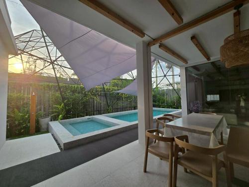 a dining room with a table and a swimming pool at The Ten Poolvilla Huahin in Hua Hin