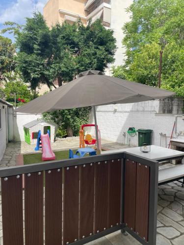 a table with an umbrella next to a playground at A-vli 63 in Volos