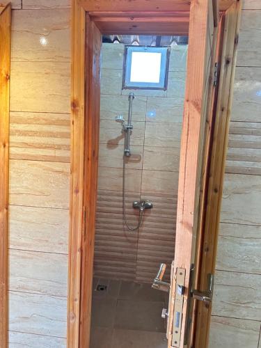una ducha en una habitación de madera con ventana en Desert Star Camp, en Wadi Rum