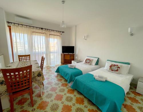 a room with two beds and a table and a television at NINFEA SEAVIEW APARTMENT - Elegant, Bright and Spacious, Steps from the Sea & Station in Nettuno