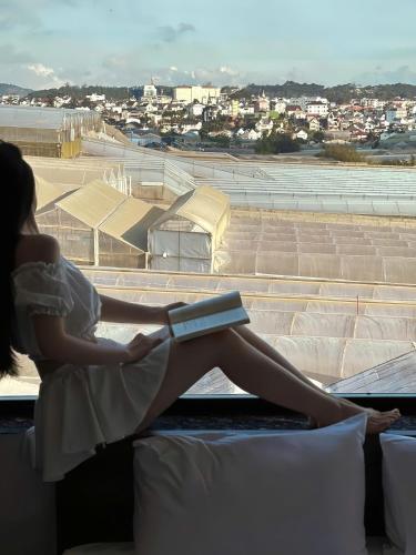 a woman sitting on a couch looking out a window at an airport at Anteaus Hotel Đà Lạt in Da Thien