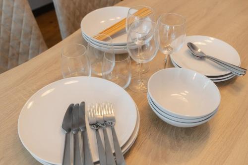a wooden table with white plates and forks and glasses at TIDA Ishigaki in Ishigaki Island