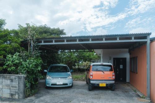 two cars parked in a parking lot next to a building at TIDA Ishigaki in Ishigaki Island