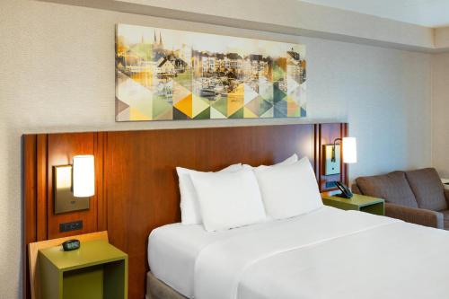 a bedroom with a white bed and a couch and a chair at Comfort Inn in Charlottetown