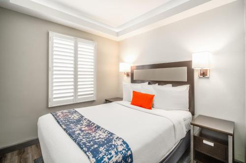a bedroom with a large white bed with an orange pillow at Inn at 50 Long Beach Convention Center in Long Beach