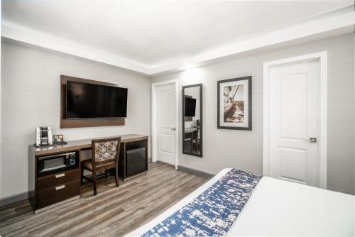 a hotel room with a bed and a desk and a tv at Inn at 50 Long Beach Convention Center in Long Beach