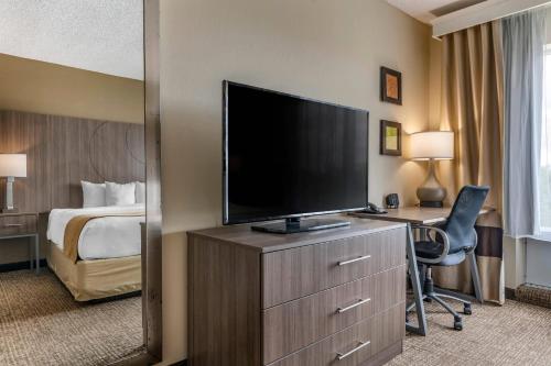 a hotel room with a television and a desk with a bed at Comfort Suites Sawgrass in Tamarac