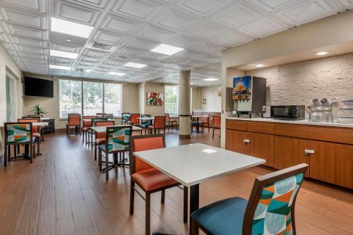 a dining room with tables and chairs and a kitchen at Comfort Suites Sawgrass in Tamarac