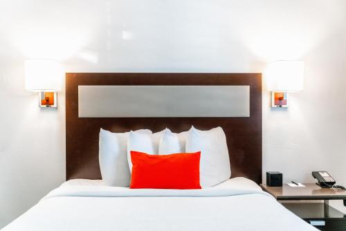 a bed with a red pillow in a hotel room at Inn at 50 Long Beach Convention Center in Long Beach