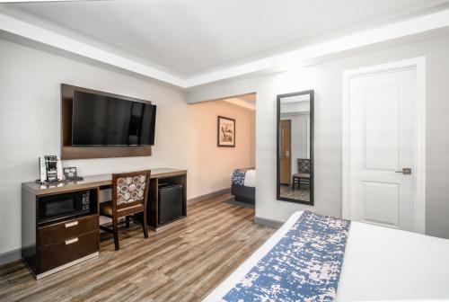 a hotel room with a bed and a desk and a tv at Inn at 50 Long Beach Convention Center in Long Beach