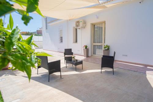 a patio with chairs and a table and a white building at From Flori in Terrasini