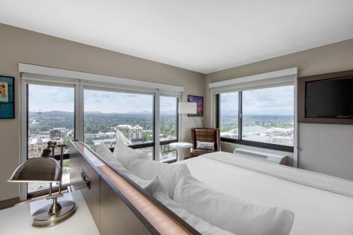 a bedroom with a large bed and large windows at Cambria Hotel Downtown Asheville in Asheville
