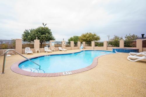 a large swimming pool with chairs at Comfort Suites University Drive in College Station